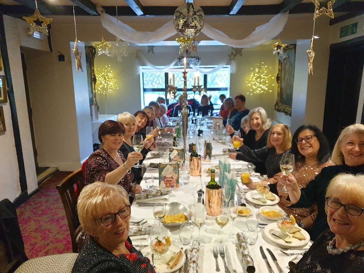 Group of people raising their glasses while seated at a long, decorated dining table with festive decor.