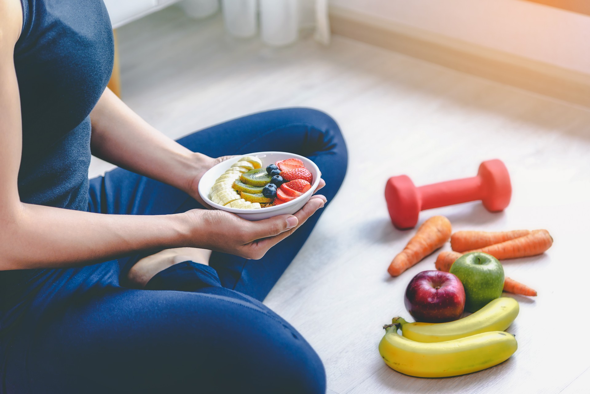 A woman holding a plate of fruits to eat after exercising to take care of her health.