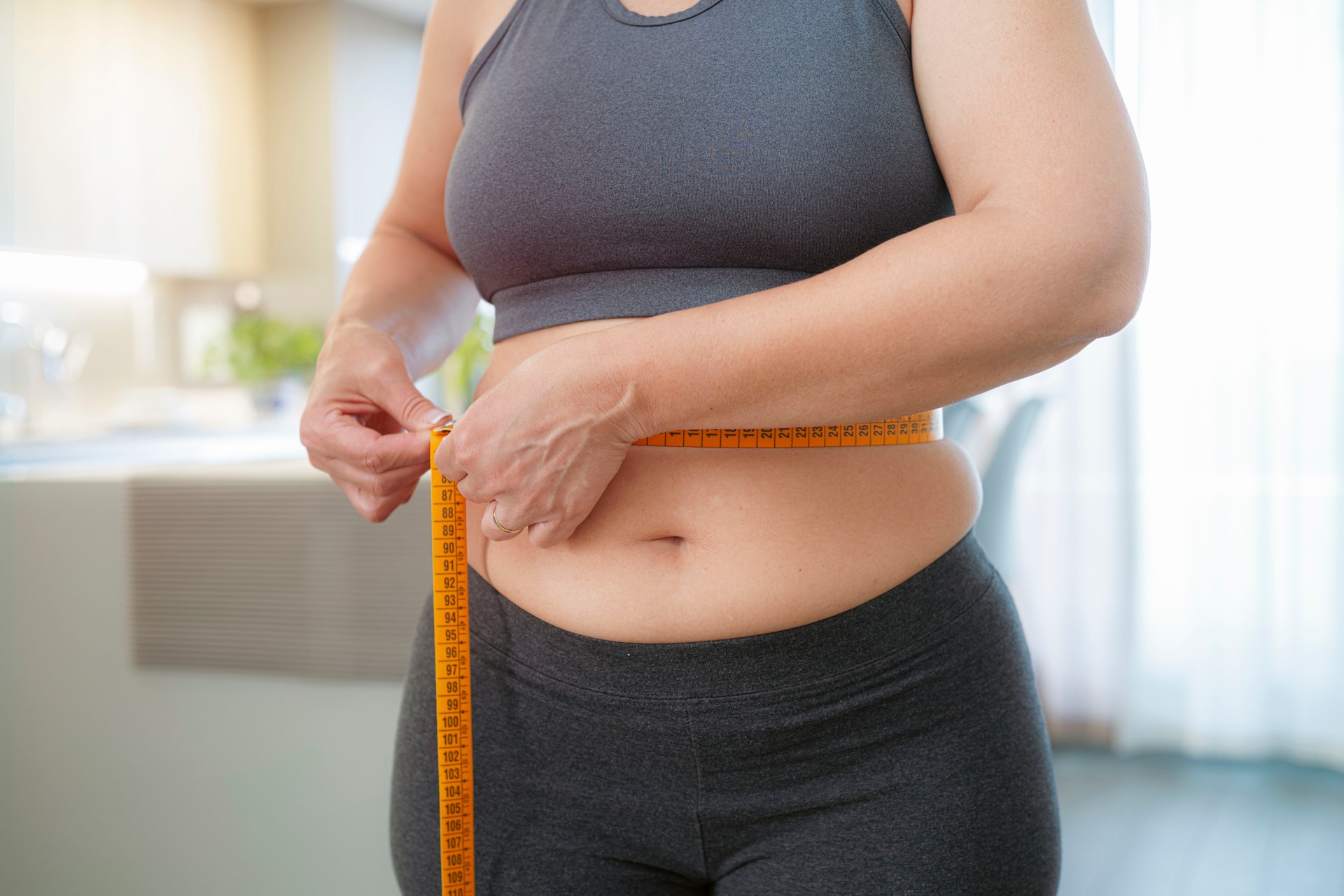 Plus size woman measuring her waist